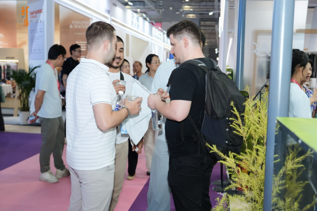 International visitors reviewing product materials in the exhibition aisle at Intertextile Shanghai 2026